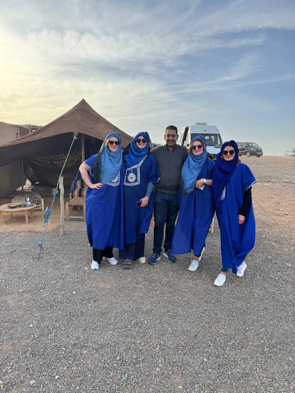 Guests at a desert camp, with the vans behind them