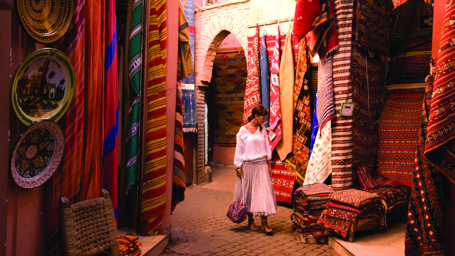 A guest walking the Marrakech souks, among rug stalls